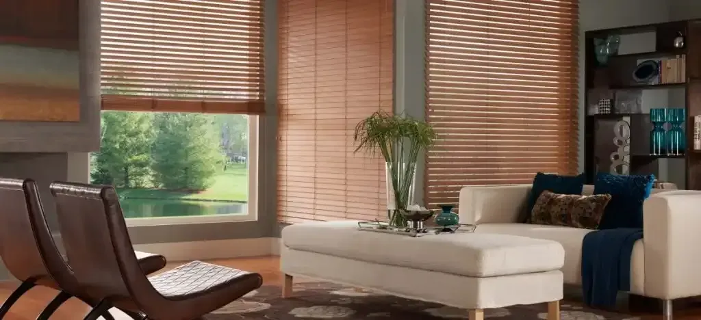 Living room with wood blinds, white couch, and two brown chairs.