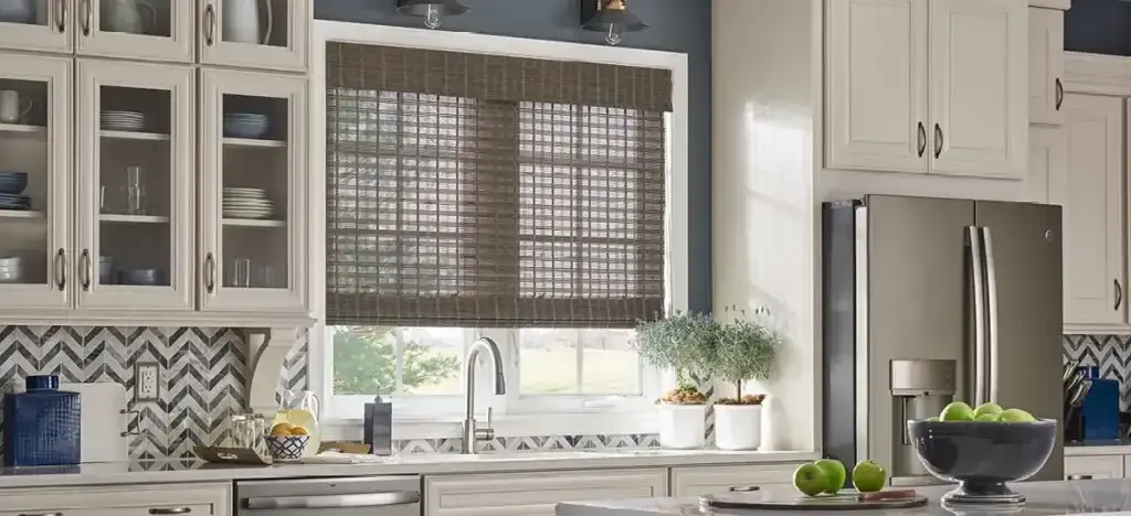 Kitchen with white cabinets and a window with natural woven shades