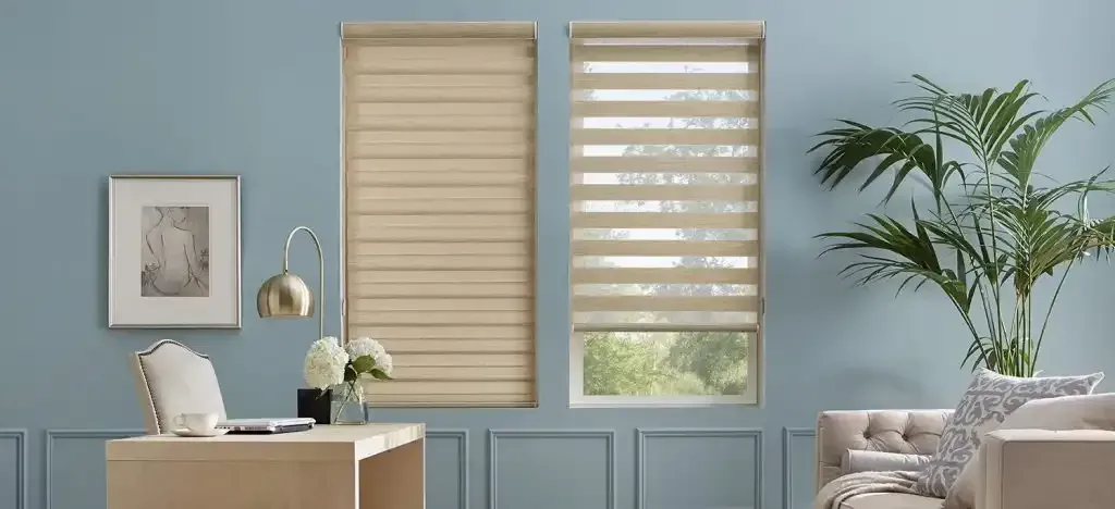 Two windows with tan blinds in a room with light blue walls, a desk, and a couch.