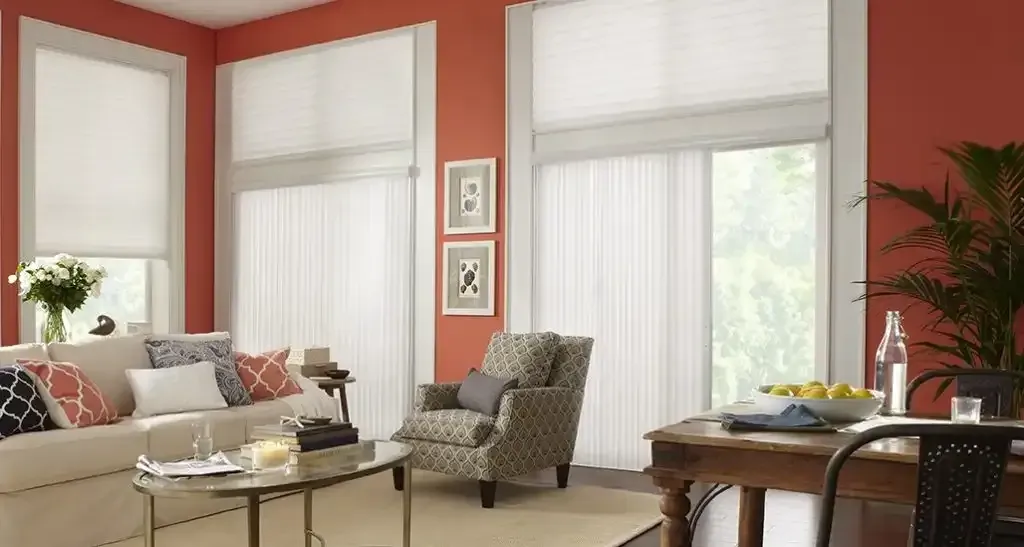 Living room with white blinds, coral walls, sofa, patterned armchair, and wooden table.