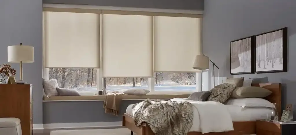 Bedroom with large windows, neutral-colored blinds, a bed, and artwork. Gray walls and natural light.
