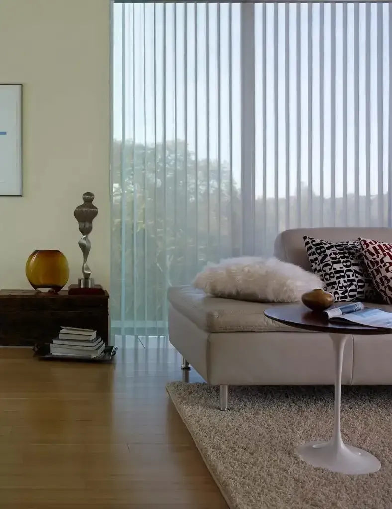 Living room with vertical blinds, light beige leather sofa, and a round side table.