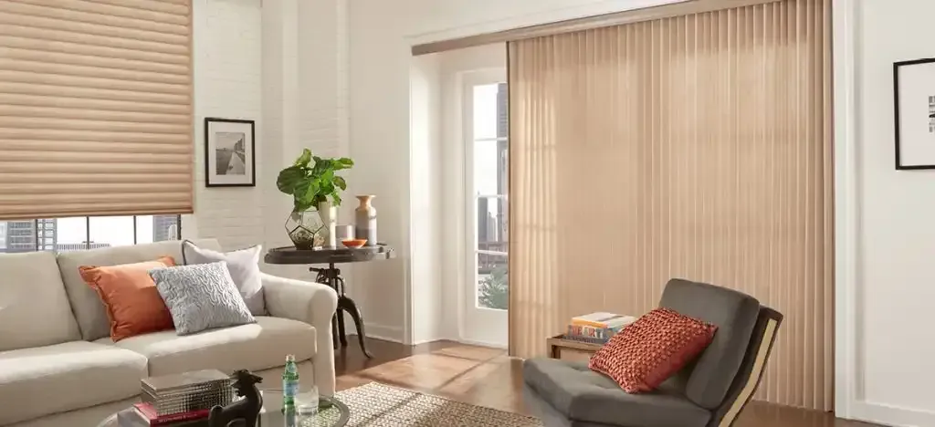 Living room with beige pleated blinds, a sofa with orange pillows, and an armchair.