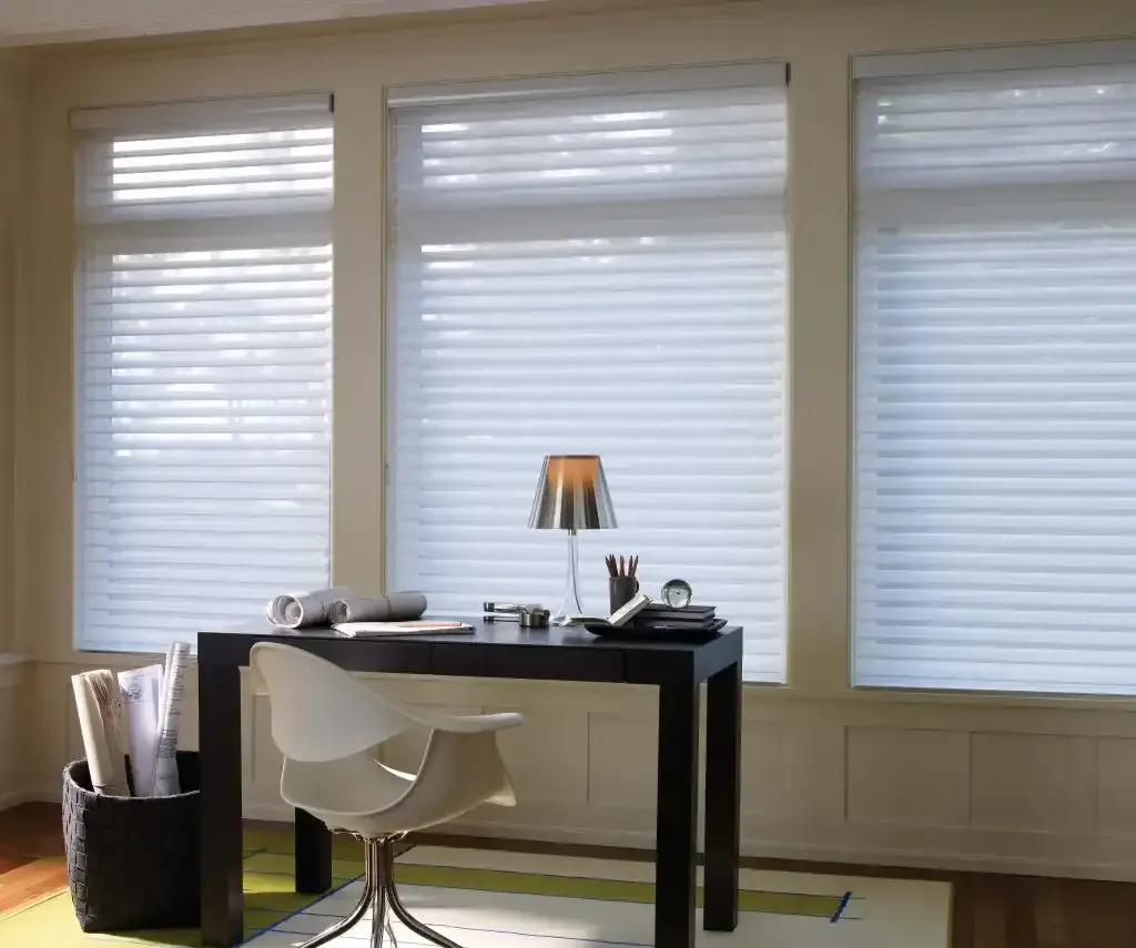 Office with desk, chair, and large windows with blinds; natural light.