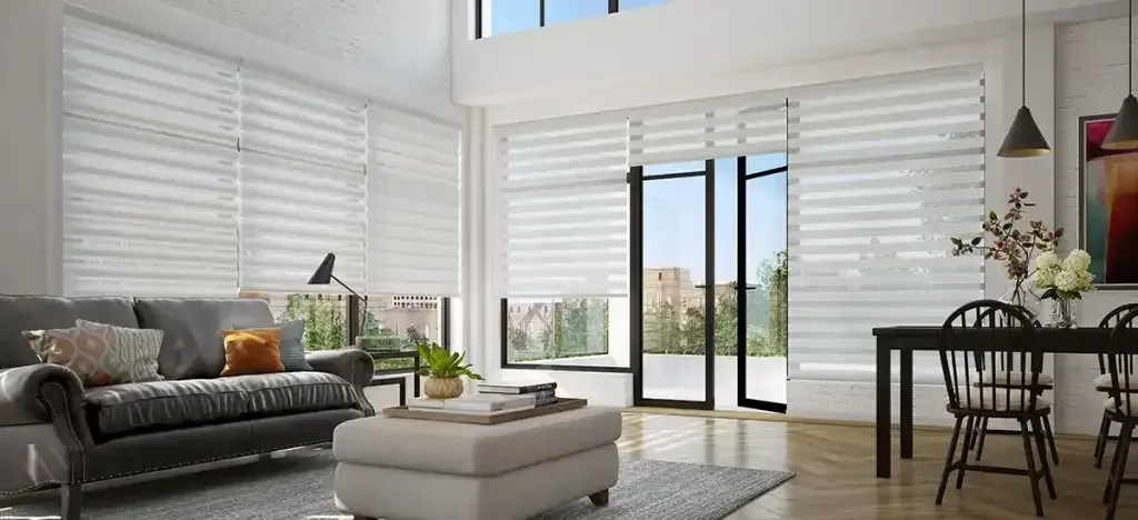 Bright modern living room with large windows, white blinds, and a dark sofa.